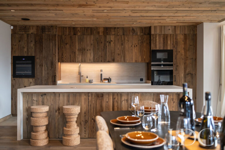 Open-plan kitchen at Chalet Lenafaju with timber cabinetry, breakfast bar and dining place settings
