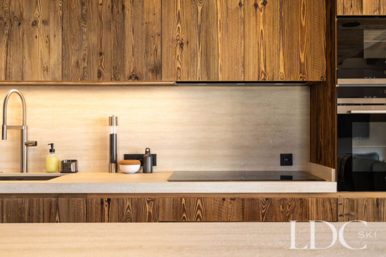 Kitchen at Chalet Lenafaju with natural timber cabinetry, stone worktops and integrated appliances