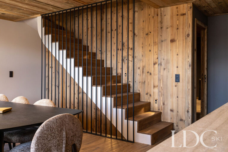Open-plan kitchen at Chalet Lenafaju beside the contemporary timber staircase