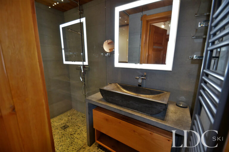 Bathroom at Chalet Malina with walk-in shower, stone basin and illuminated mirror