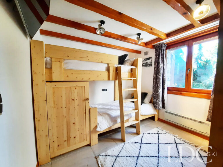 Bunk bedroom at Chalet Malina with wooden bunk beds, exposed ceiling beams and large window