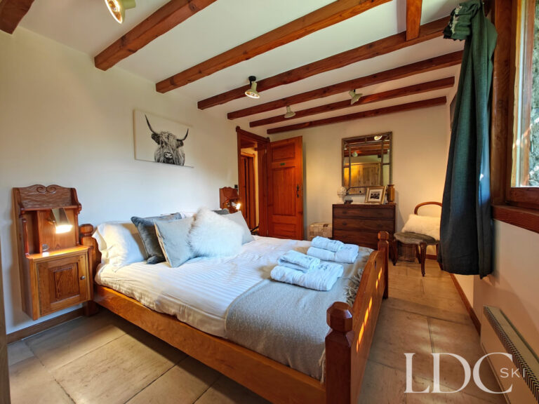 Double bedroom at Chalet Malina with traditional wooden furniture and exposed ceiling beams