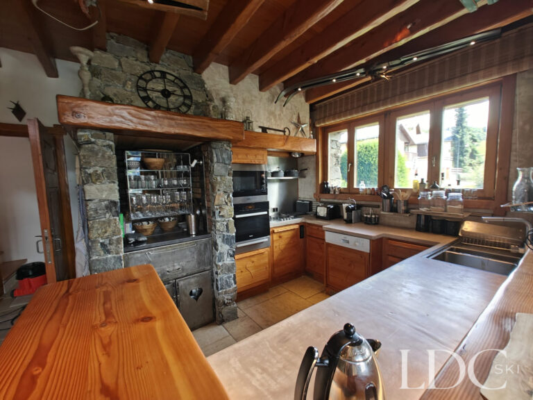 Kitchen at Chalet Malina with wooden cabinetry, stone walls and exposed ceiling beams