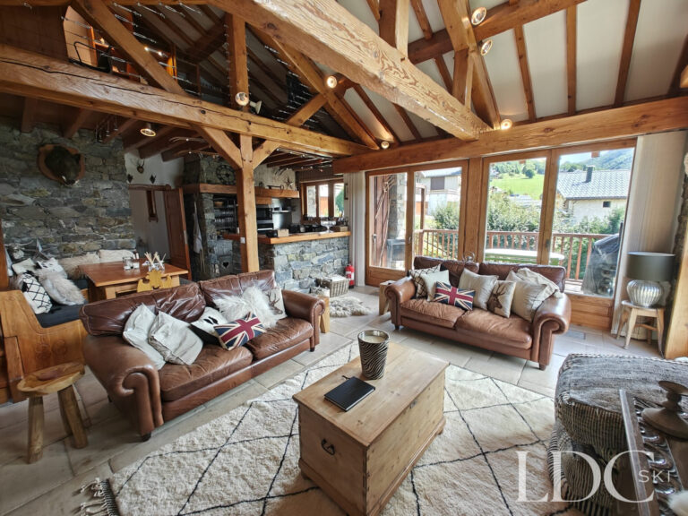 Spacious living area at Chalet Malina with sofas, exposed beams, stone walls and large windows