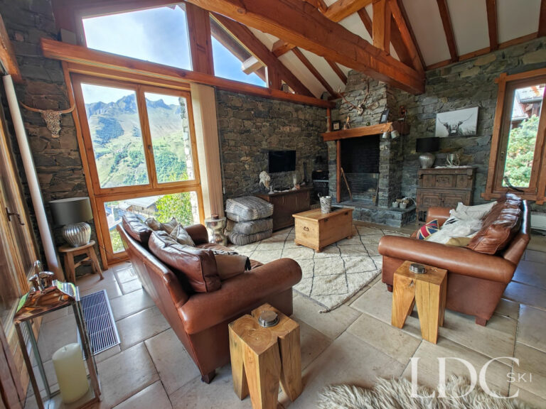 Lounge at Chalet Malina with stone walls, exposed timber beams and mountain views through large windows