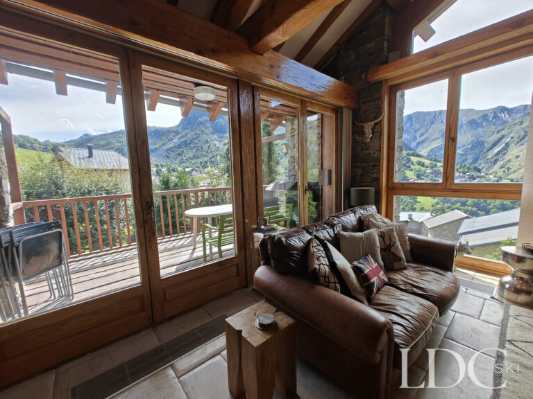 Lounge at Chalet Malina with large windows opening onto the balcony and mountain views in St Martin de Belleville
