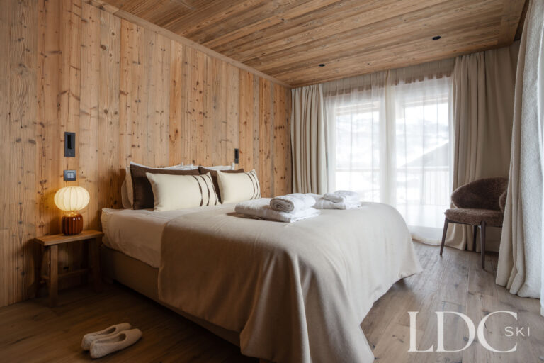 Double bedroom at Chalet Montana with natural timber walls and warm bedside lighting
