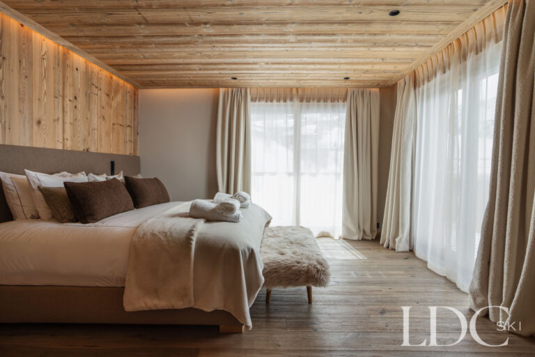 Double bedroom at Chalet Montana with timber walls and large doors opening towards the balcony