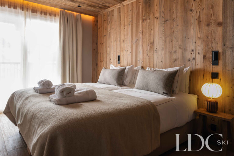 Double bedroom at Chalet Montana with timber walls, soft furnishings and large windows