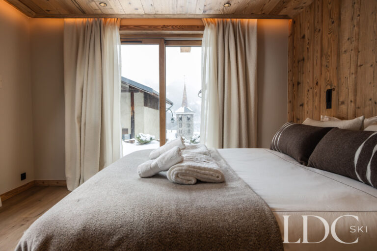 Double bedroom at Chalet Montana with timber walls and doors opening onto the balcony