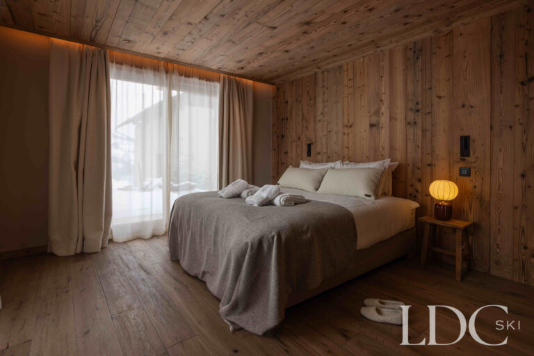 Double bedroom at Chalet Montana with timber panelling and mountain views through large windows