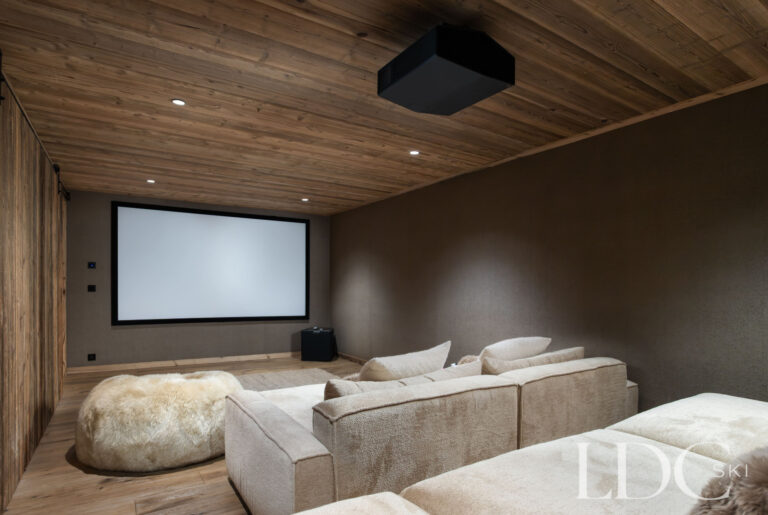 Private cinema room at Chalet Montana with large projection screen and comfortable sofa seating