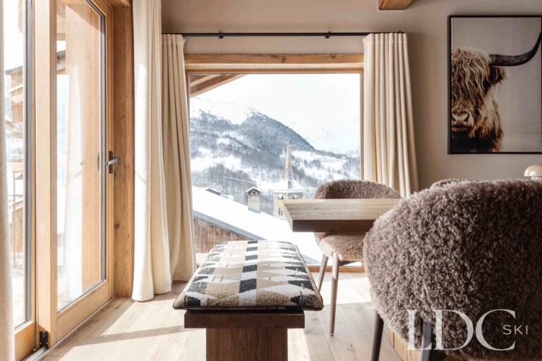 Dining area at Chalet Montana beside large windows overlooking the mountains in St Martin de Belleville