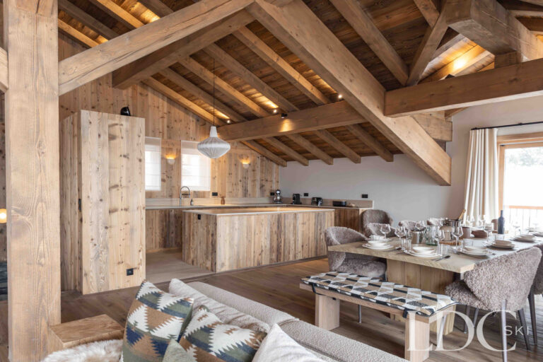 Open-plan living area at Chalet Montana with lounge, kitchen and exposed timber beams