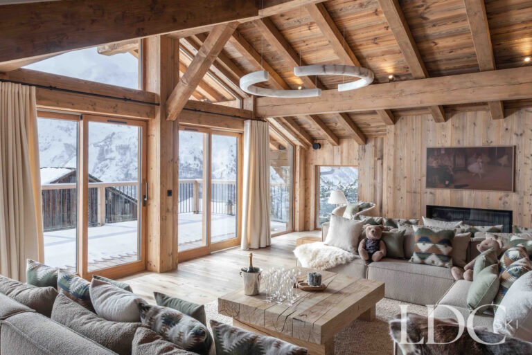 Living room at Chalet Montana with large windows, exposed timber beams and mountain views in St Martin de Belleville