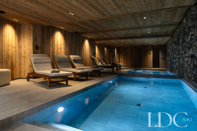 Indoor swimming pool at Chalet Montana with stone walls, loungers and atmospheric lighting