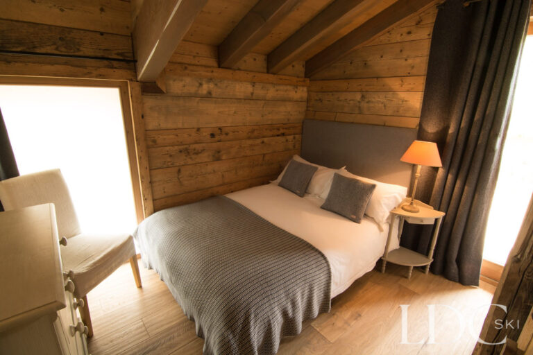 Double bedroom at Chalet Riondaz with exposed beams and doors opening onto a balcony