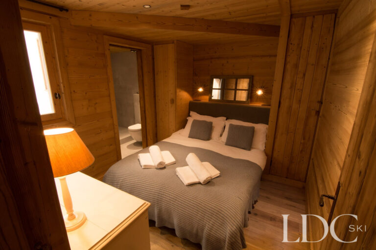 Double bedroom at Chalet Riondaz with warm timber panelling and en-suite access