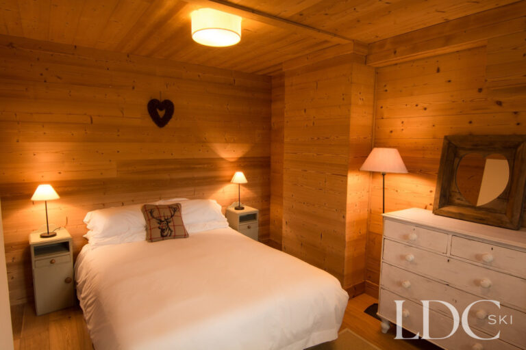 Traditional double bedroom at Chalet Riondaz with timber walls and alpine-style furnishings