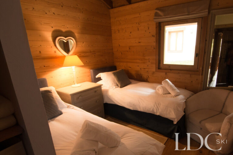 Twin bedroom at Chalet Riondaz with timber walls and alpine-style furnishings