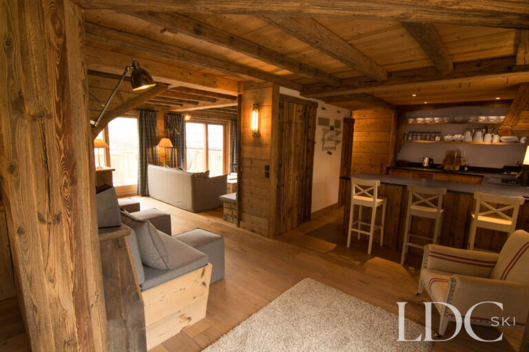 Open-plan living area at Chalet Riondaz with lounge, kitchen, exposed beams and timber interiors