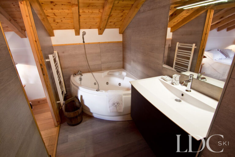 Bathroom at Chalet Saint Peres with corner bath, basin and exposed timber ceiling