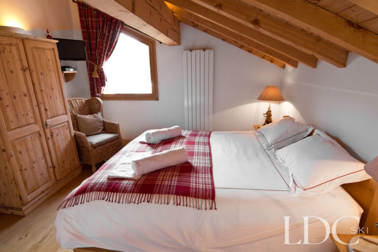 Double bedroom at Chalet Saint Peres beneath a sloping timber ceiling