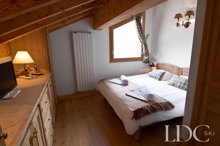 Double bedroom at Chalet Saint Peres with exposed timber ceiling and alpine-style furnishings