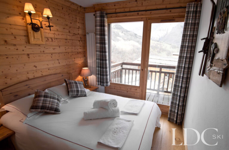 Double bedroom at Chalet Saint Peres with timber walls and doors opening onto a balcony