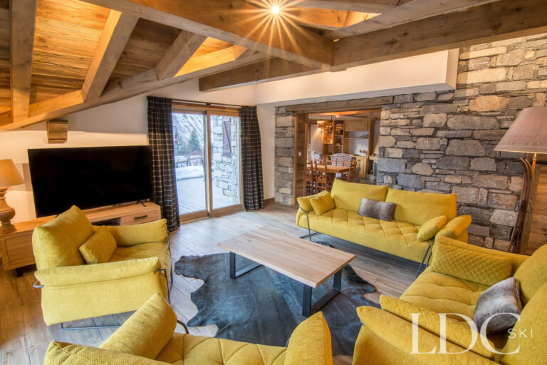 Lounge at Chalet Saint Peres with sofas, exposed beams and large stone fireplace