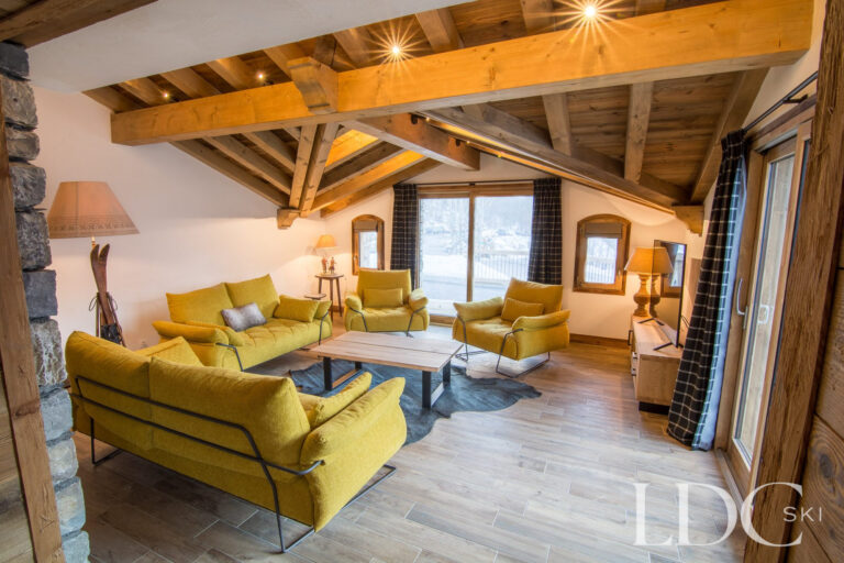Spacious lounge at Chalet Saint Peres with sofas, exposed timber beams and mountain views