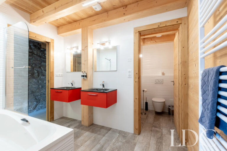 Family bathroom with bath, twin red basins and timber detailing at La Ferme de la Couttetaz