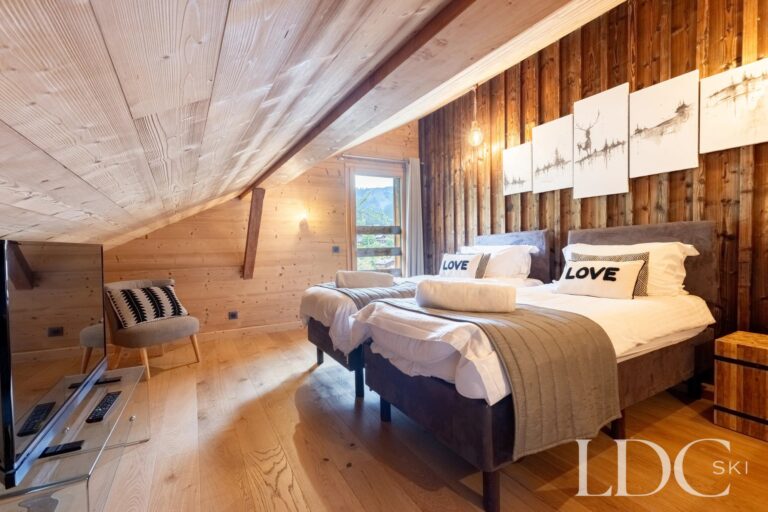 Double bedroom with timber ceiling and Alpine-inspired décor at La Ferme de la Couttetaz