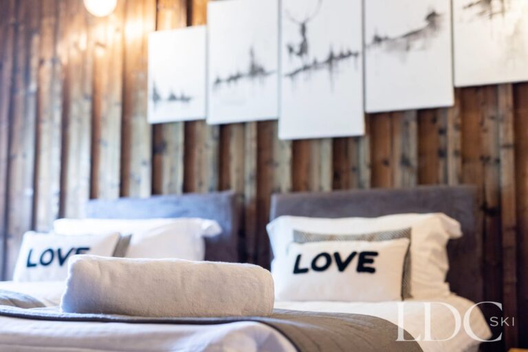 Double bedroom with rustic timber feature wall and Alpine detailing at La Ferme de la Couttetaz