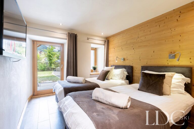 Twin bedroom with timber wall and garden access at La Ferme de la Couttetaz