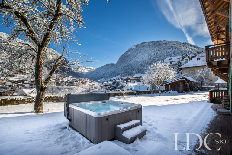 Outdoor hot tub with snowy mountain views at La Ferme de la Couttetaz in Morzine