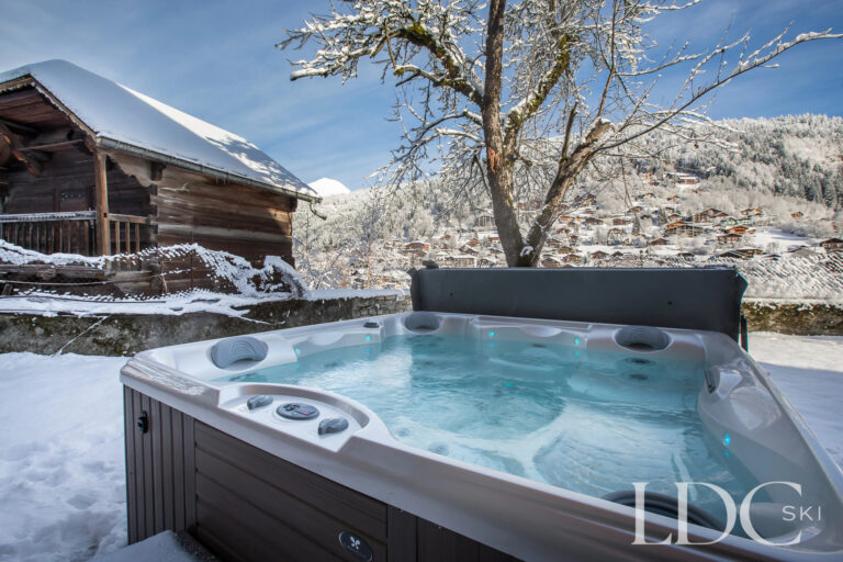 Outdoor hot tub in the snowy garden at La Ferme de la Couttetaz in Morzine