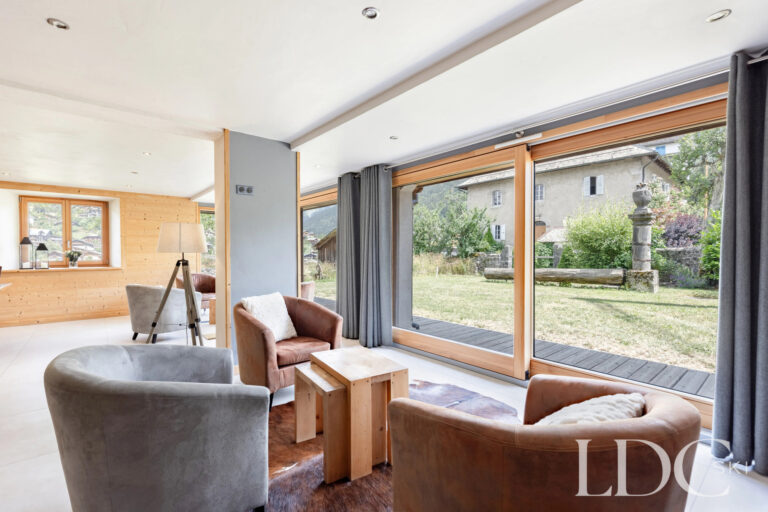 Lounge with large windows and views across the garden at La Ferme de la Couttetaz