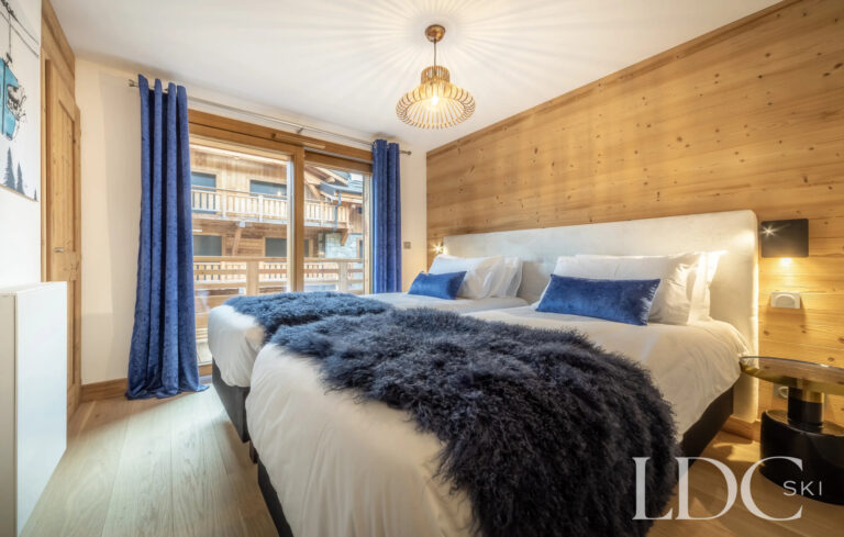 Les Deux Frères double bedroom with timber feature wall and doors opening onto the balcony