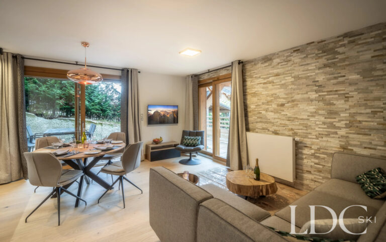 Les Deux Frères lounge and dining area with stone feature wall and doors to the balcony