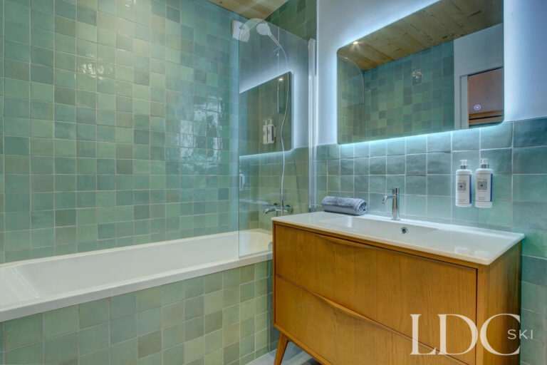 Green tiled bathroom with bath and vanity at Piste Bleue in Morzine