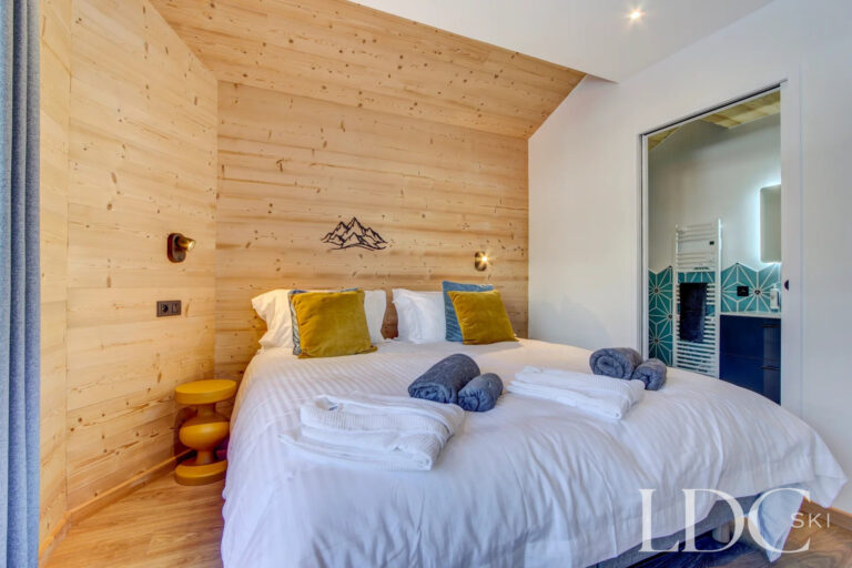 Twin bedroom with timber feature wall and en-suite bathroom at Piste Bleue