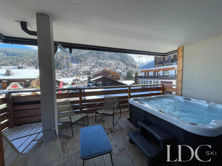 Outdoor hot tub on the covered balcony at Piste Bleue