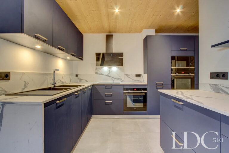 Contemporary blue kitchen with marble-effect worktops at Piste Bleue