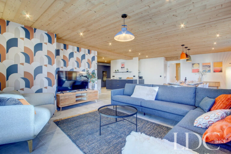 Contemporary lounge with blue sofas and patterned feature wall at Piste Bleue