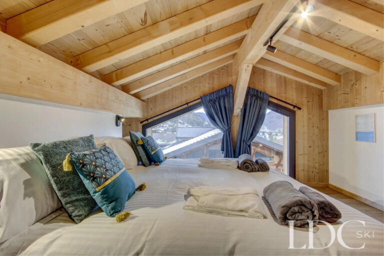 Piste Noire bedroom beneath a vaulted timber ceiling with large sloping window