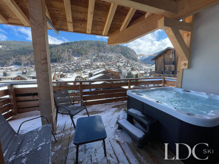 Piste Noire outdoor hot tub on the covered balcony overlooking Morzine and the mountains