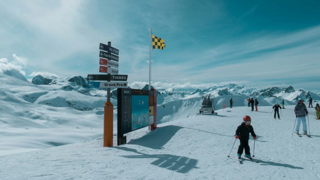 Skiers beside a piste sign on the snow-covered slopes of Val d'Isère. © Nicolas Peyrol / Unsplash
