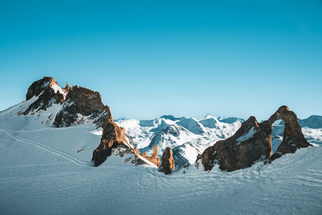 Snow-covered mountain peaks beneath blue skies in Val d'Isère. © Ryan Klaus / Unsplash