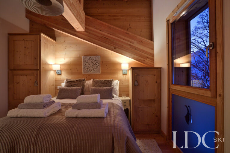 Double bedroom with warm timber interiors and evening mountain views at Chalet Aphylla